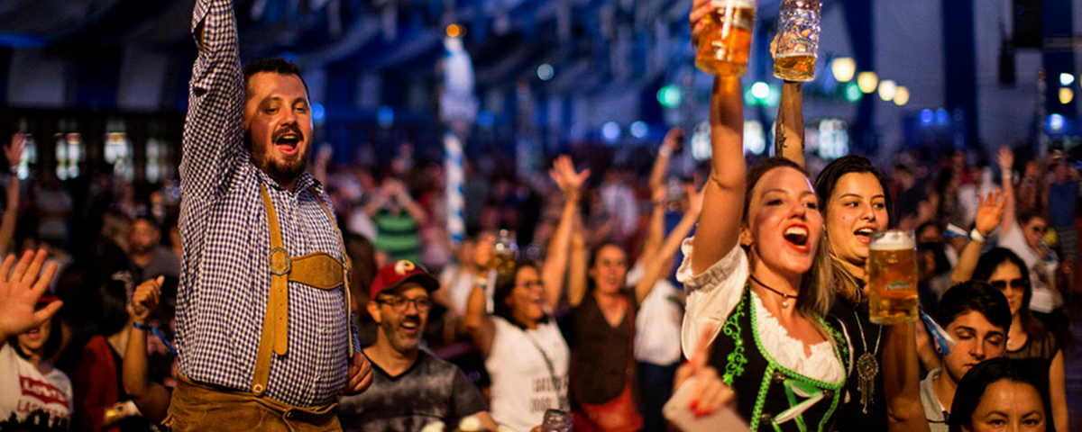 Pessoas animadas e vestindo trajes típicos alemães durante a São Paulo Oktoberfest. 